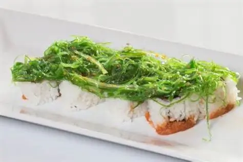 Sushi roll covered with fresh seaweed salad, featuring a unique green - topped appearance and a light at Sushi Heaven, a Japanese restaurant in Saratoga